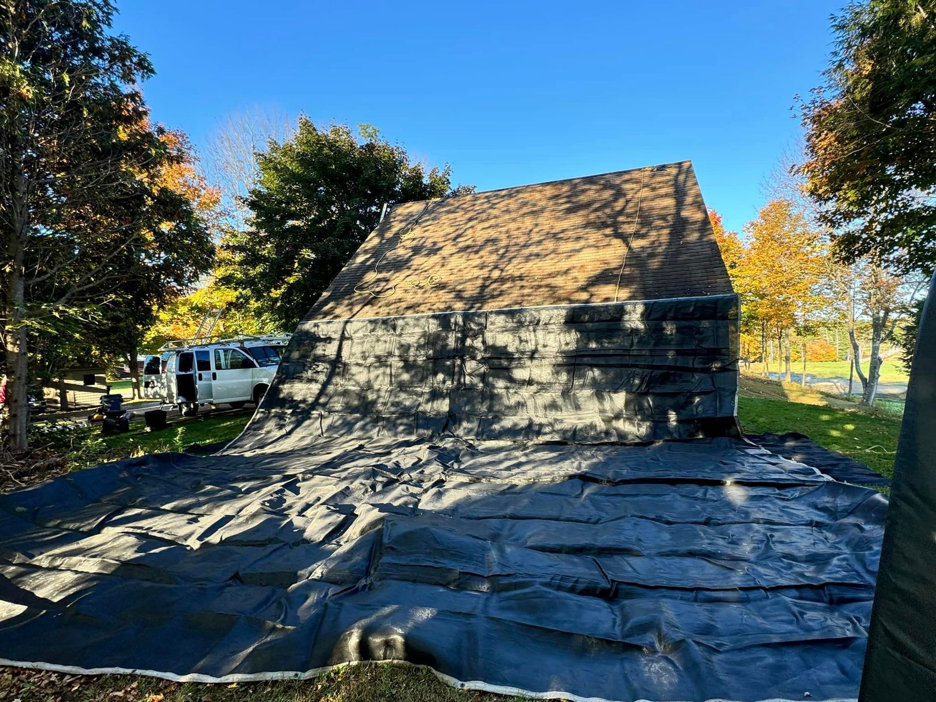 The roof of a house is covered with a black tarp.