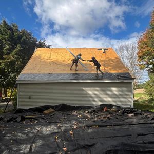 Two men are working on the roof of a garage.