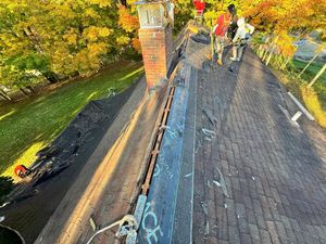 A group of people are working on the roof of a house.