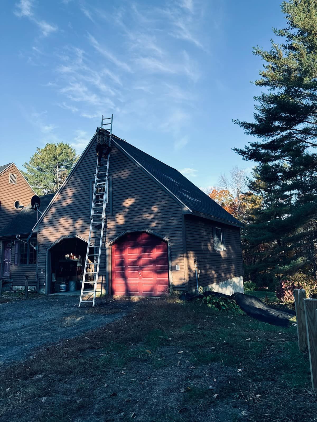 A house with a red garage door and a ladder on the roof.