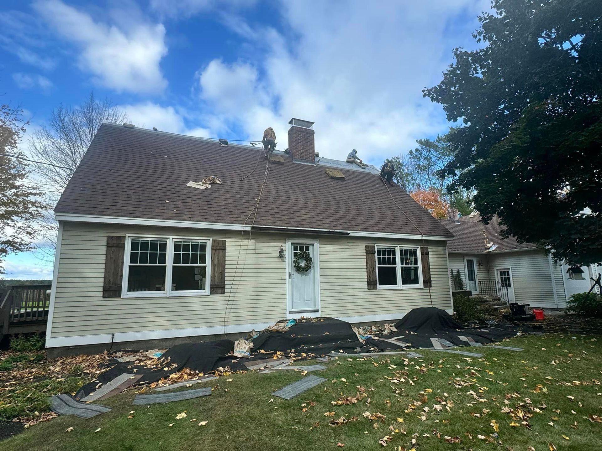 A house with a brown roof is sitting on top of a lush green field.