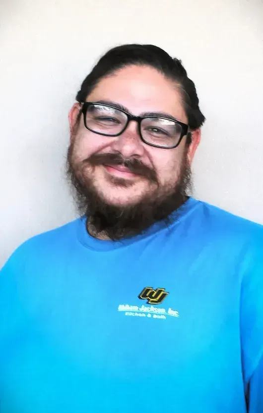 Smiling person in glasses and a blue shirt against a plain white background