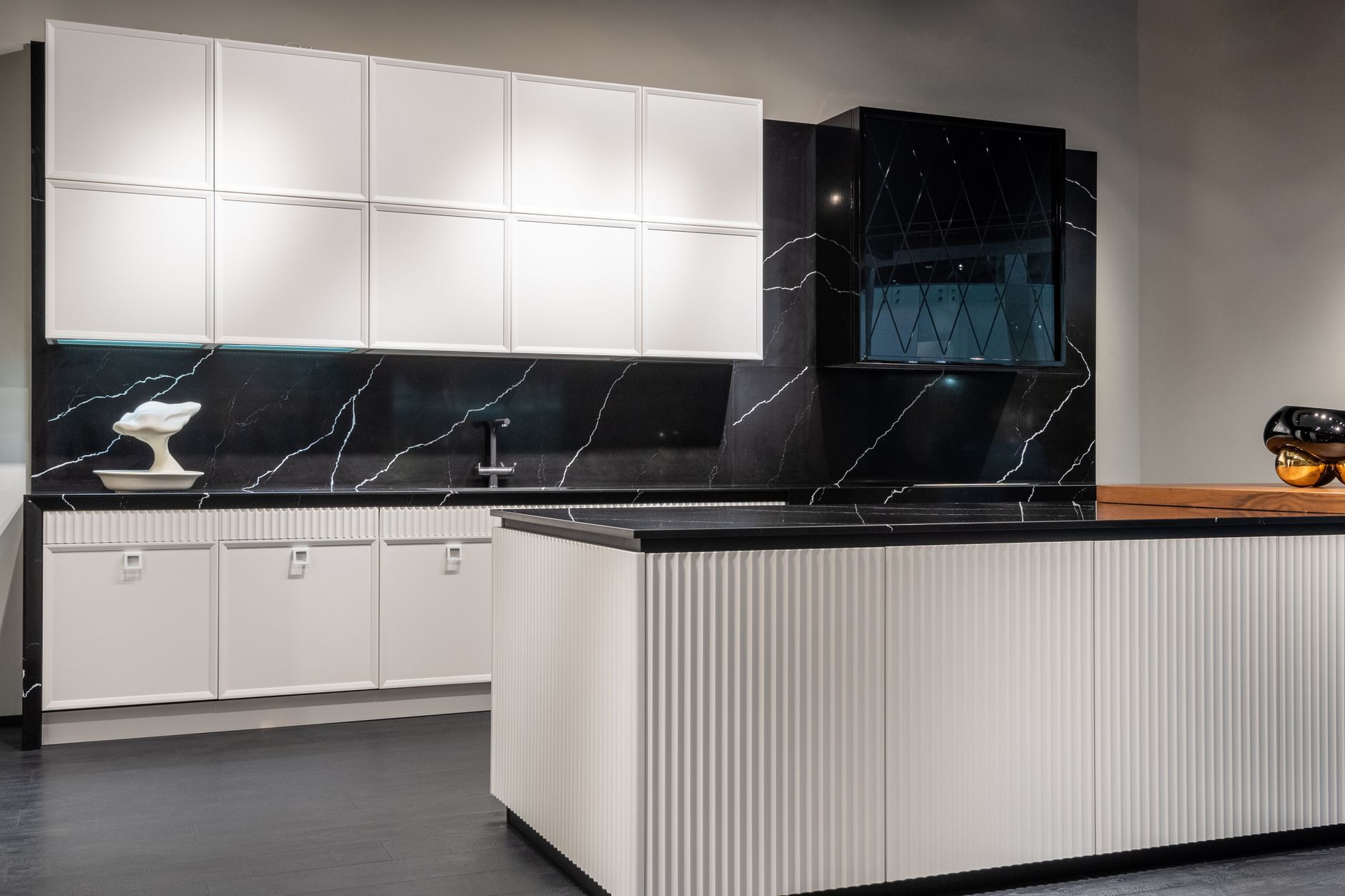 Modern kitchen with white cabinets, black marble backsplash, and a large white island