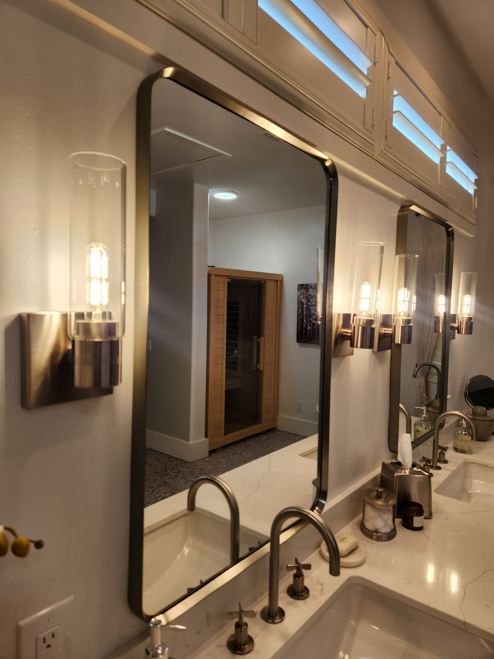 Bathroom vanity with mirror, brass sconces, and white countertop sink