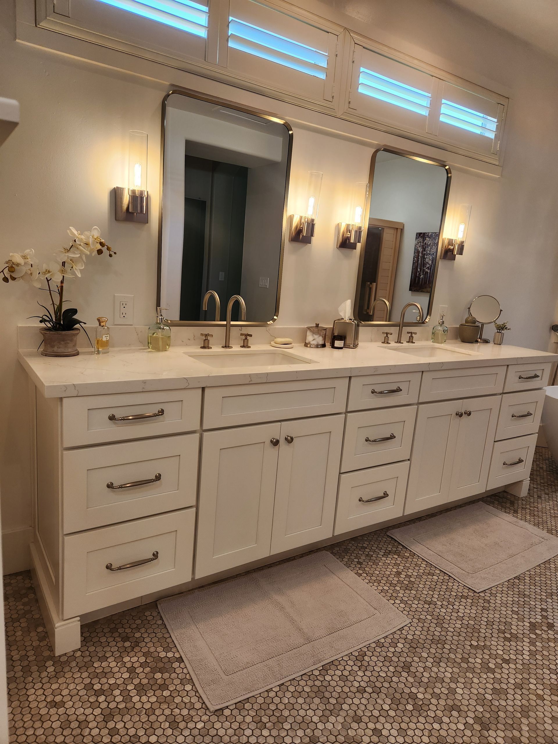 Elegant double vanity with mirrors and wall sconces in a cream-colored bathroom
