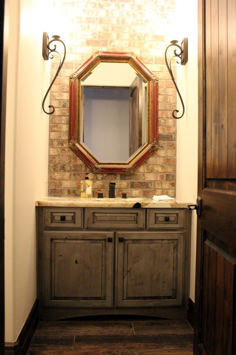 Bathroom vanity with octagonal mirror, wall sconces, and dark wood cabinet.