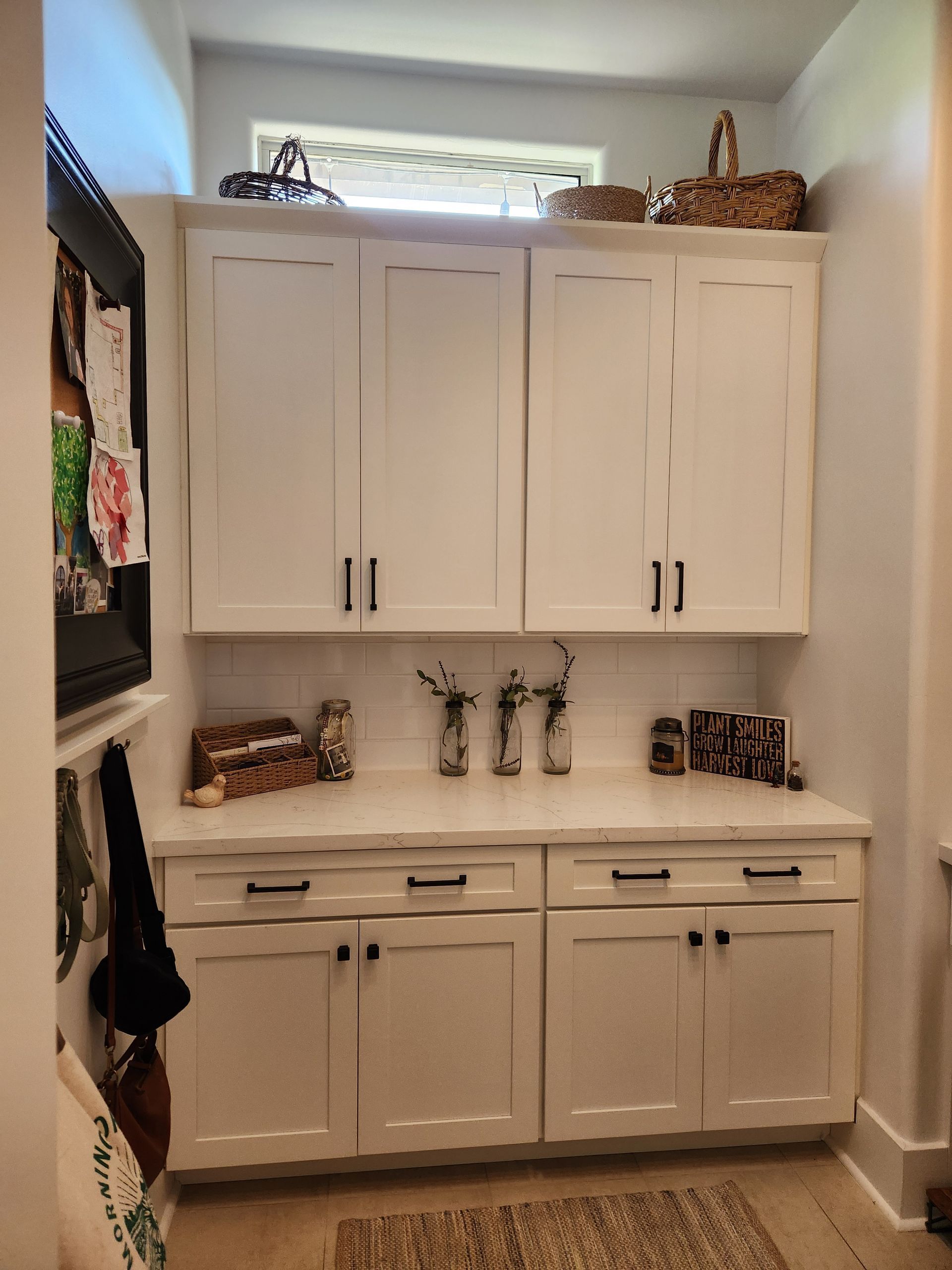 Built-in white cabinets and drawers with baskets and decor in a bright laundry room