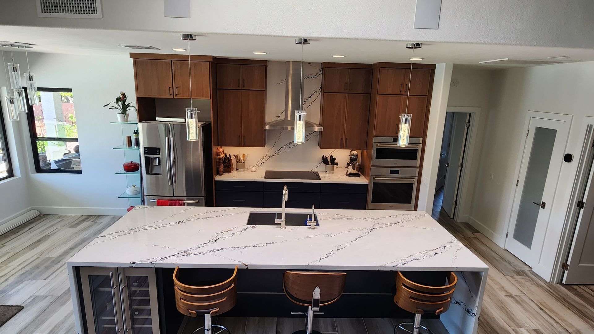 Modern kitchen with large island, bar stools, stainless fridge, and wood cabinets