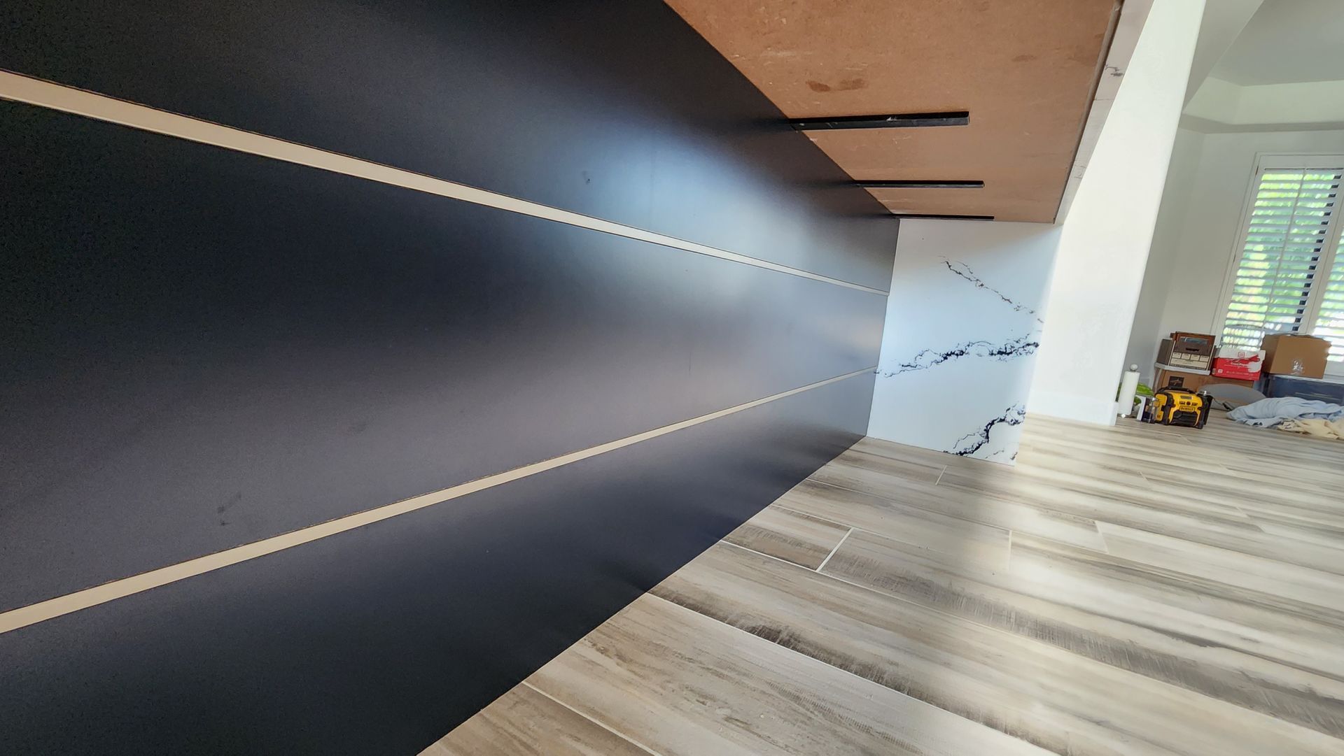 Modern room interior with dark wall, light wood floor, and window blinds on the right