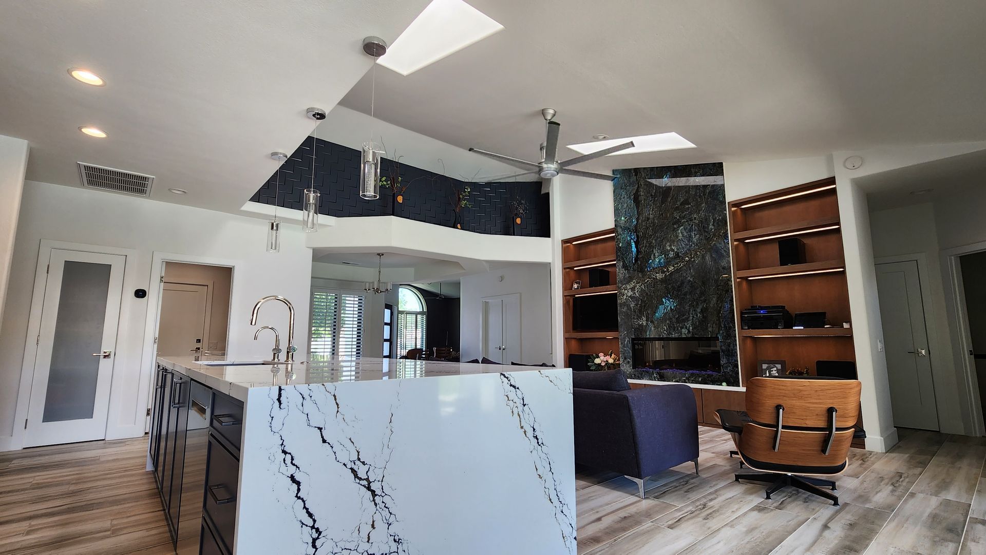 Modern lobby with white marble reception desk, ceiling fans, glass doors, and shelves with decorative items