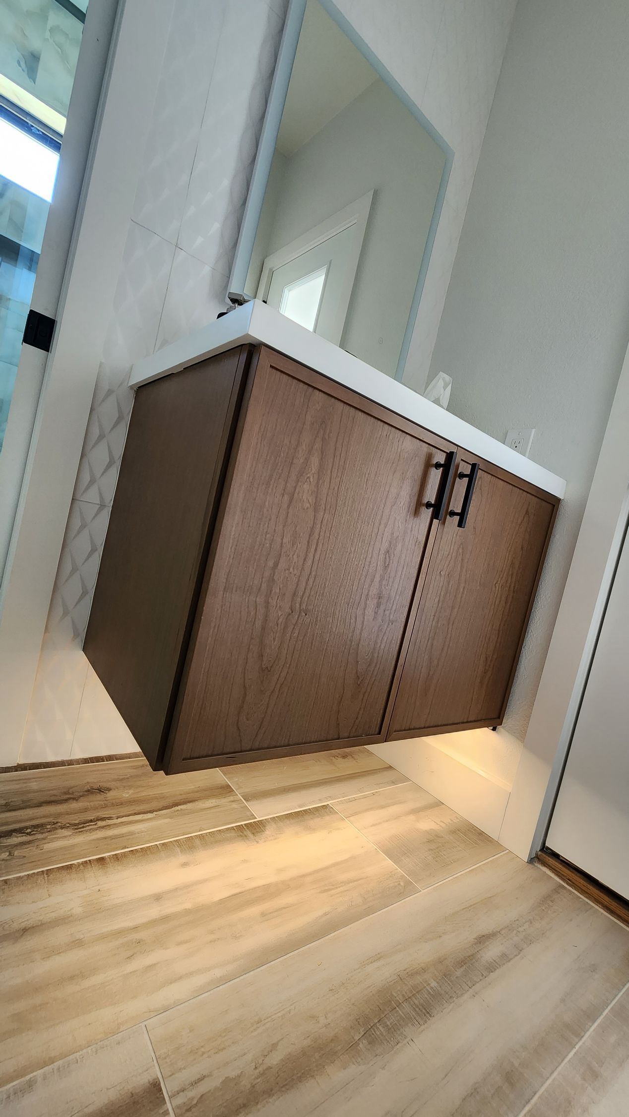 Dark wood cabinet with white countertop in a narrow hallway with light wood flooring.