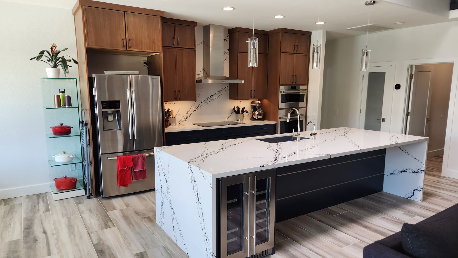 Modern kitchen with wood cabinets, stainless steel appliances, and a white marble island with barstools