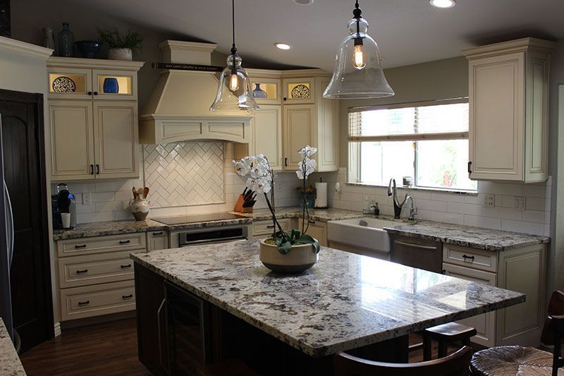Modern kitchen with granite island, cream cabinets, pendant lights, and a large window over the sink.