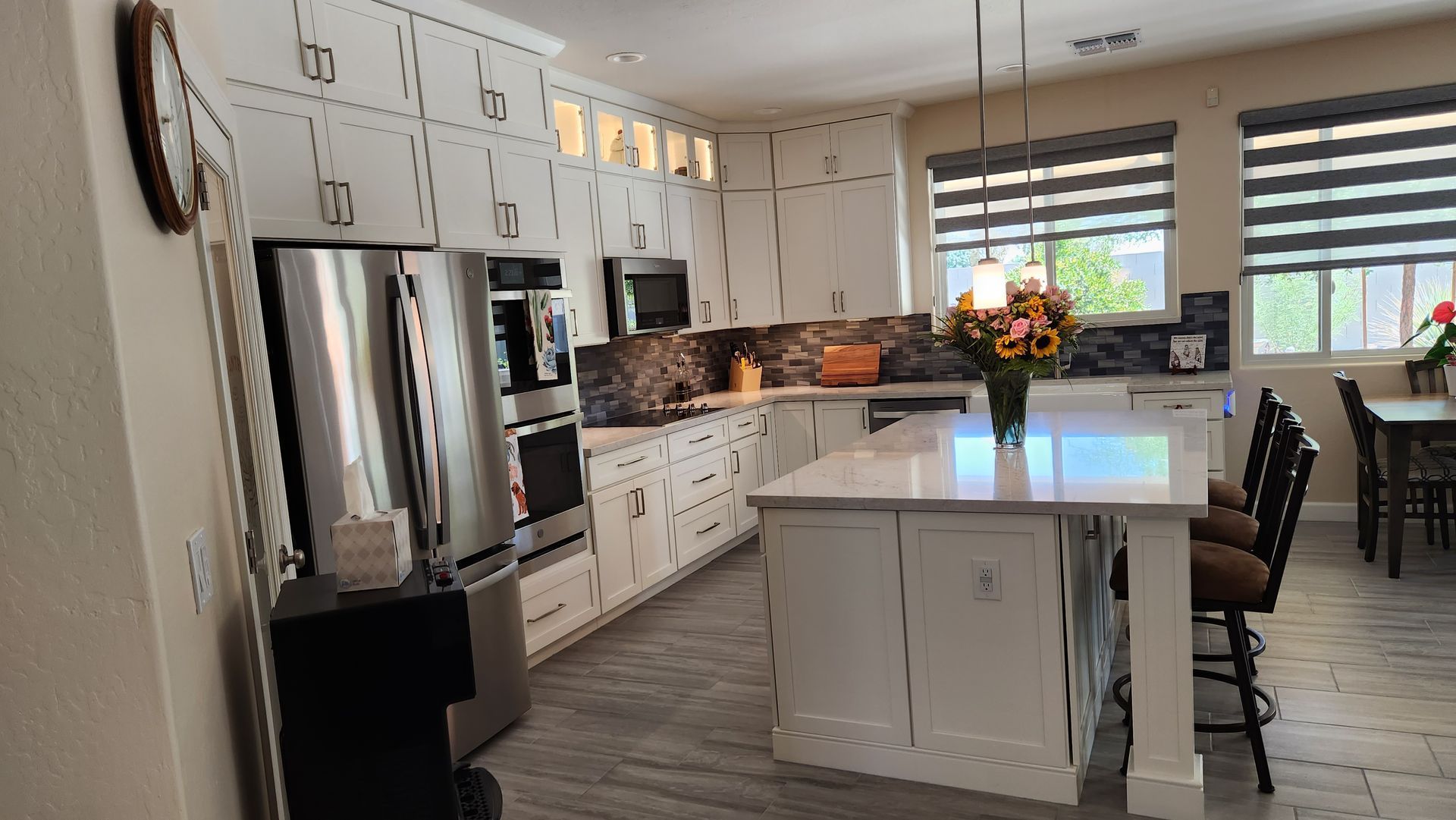 Bright modern kitchen with white cabinets, stainless appliances, island, and flowers by a window