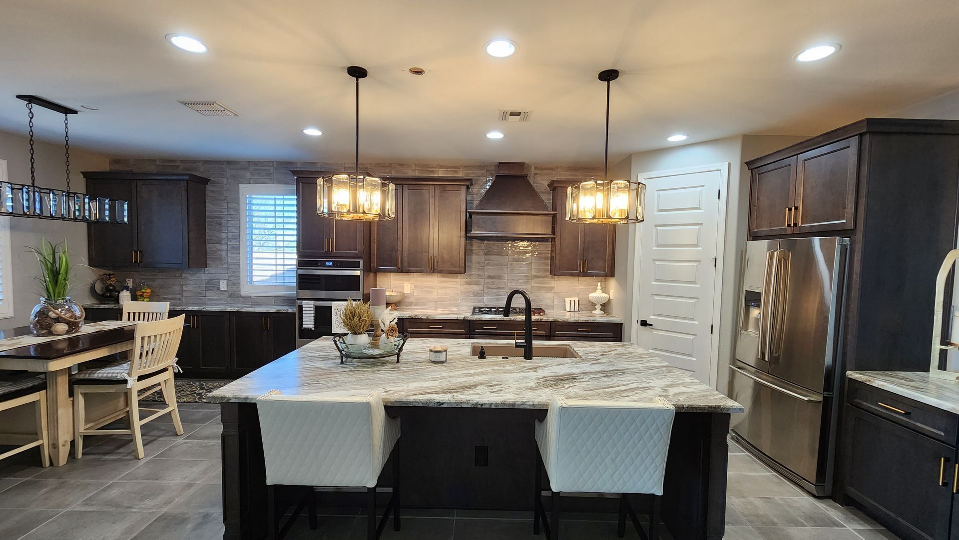 Modern kitchen with dark cabinets, granite island, pendant lights, and stainless steel appliances