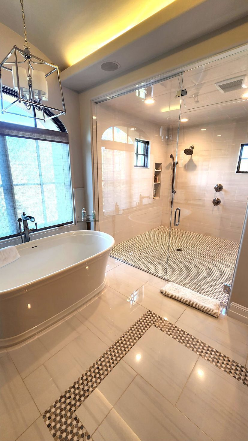 Bright modern bathroom with freestanding tub, glass shower, and mosaic tile floor and walls