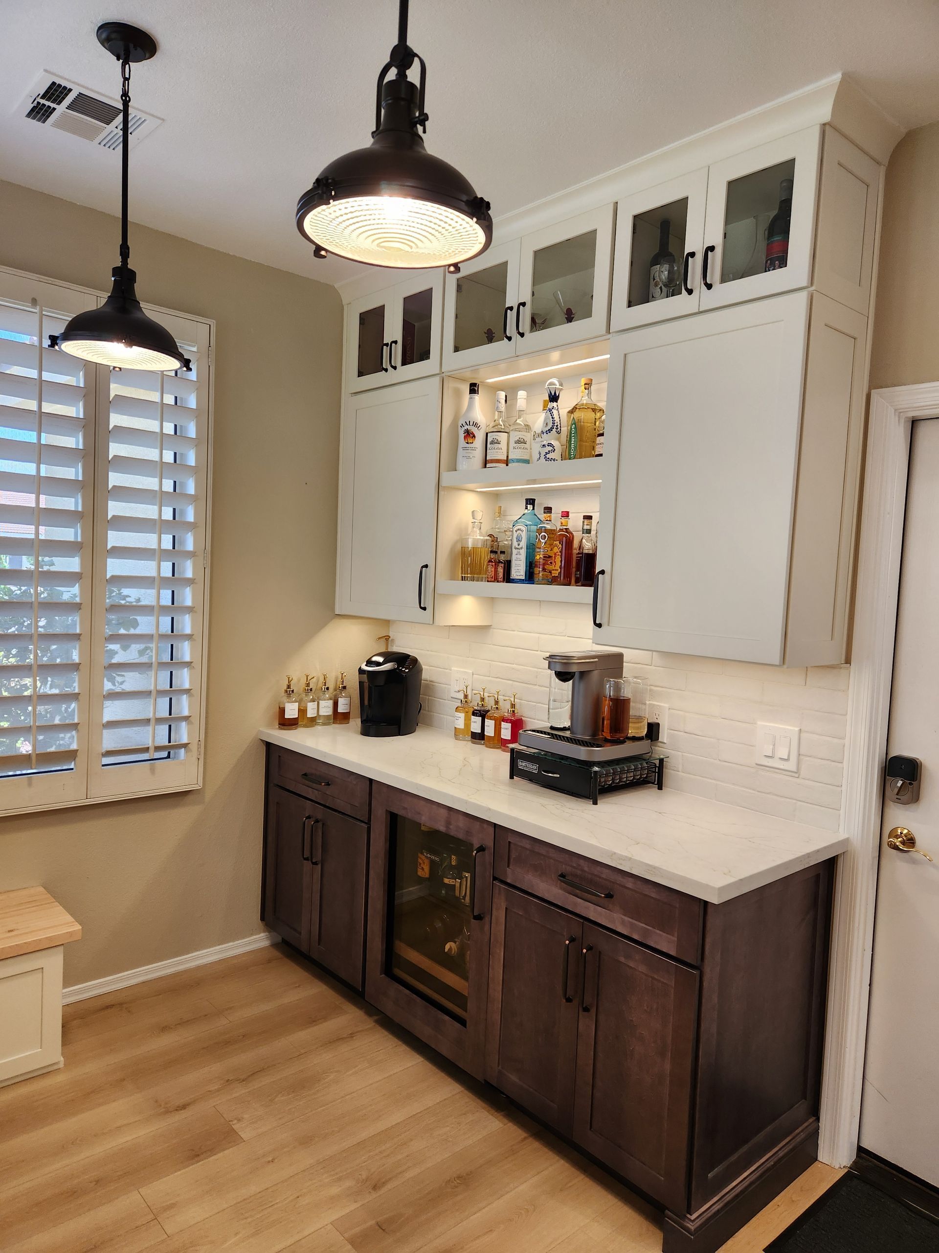 Modern kitchen with dark wood cabinets, white backsplash, open shelves, and pendant lights near a window