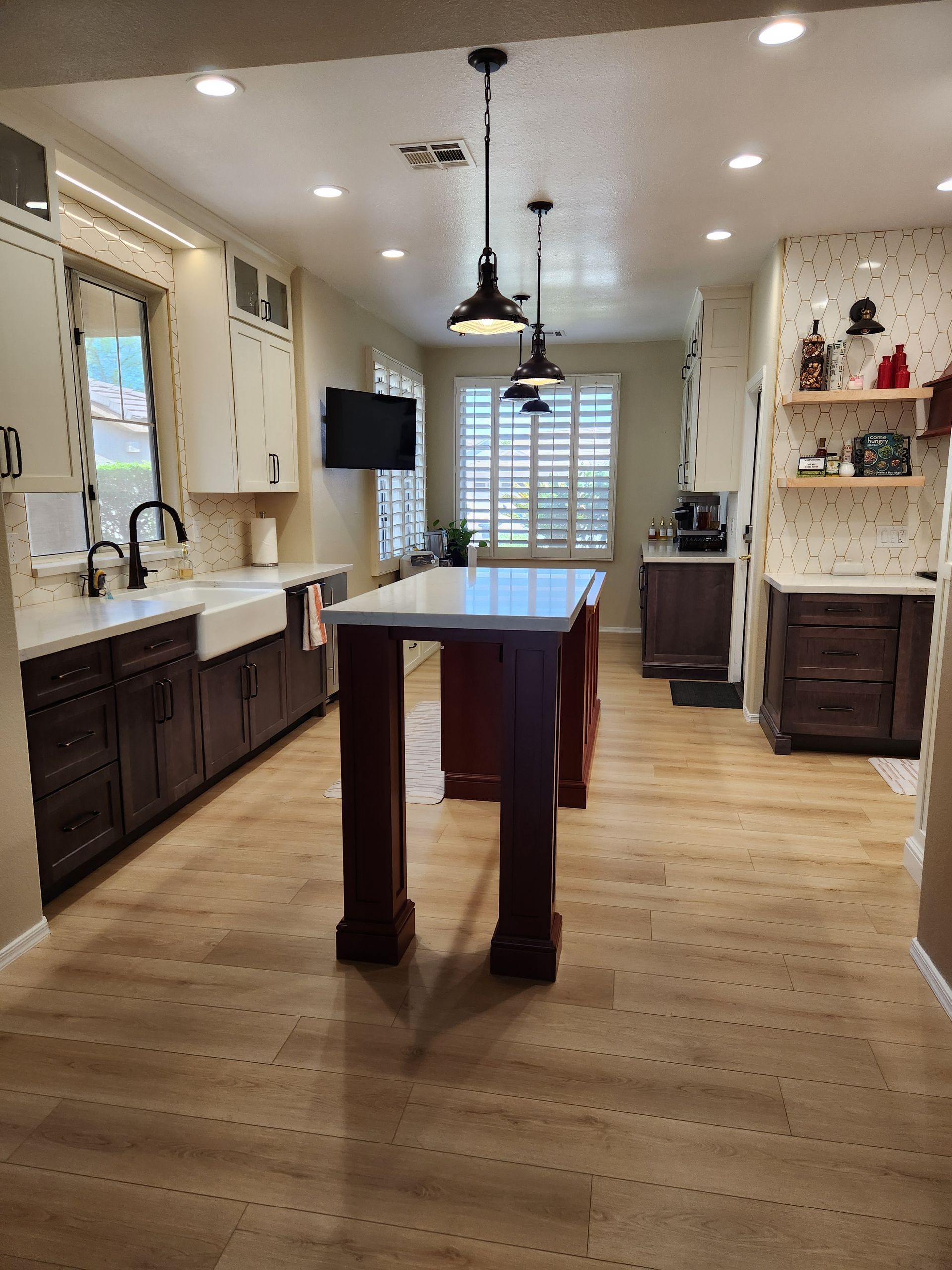 Bright kitchen with dark cabinets, long island, pendant lights, and wood floors