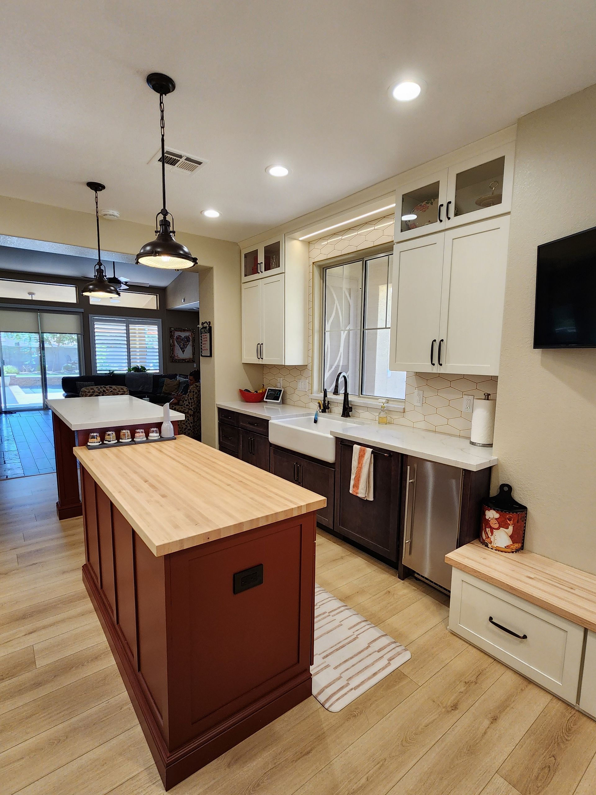 Bright kitchen with a wood island, white cabinets, and a view into a dining area and patio.