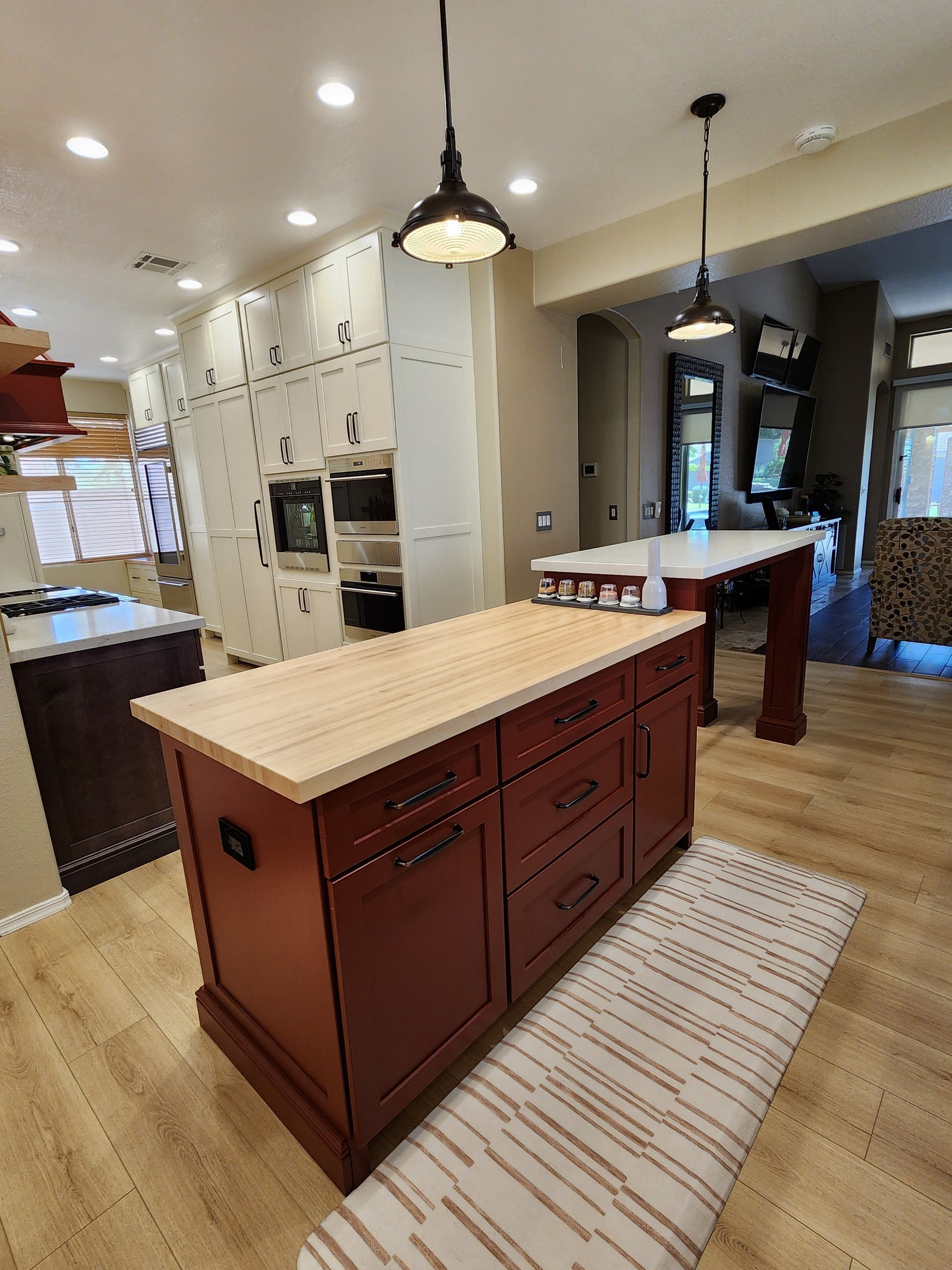 Kitchen with red island, light wood countertop, and white cabinets in a modern home interior