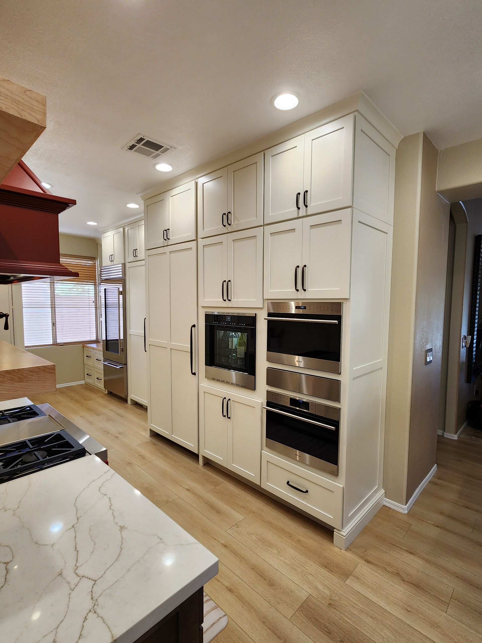Bright kitchen with white built-in cabinets, wood floors, and marble countertop