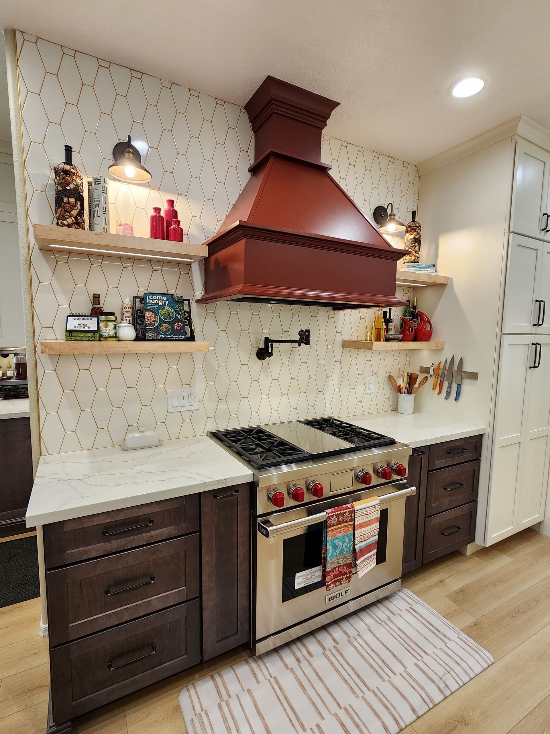 Modern kitchen with copper range hood, white countertops, dark cabinets, and a large stove.