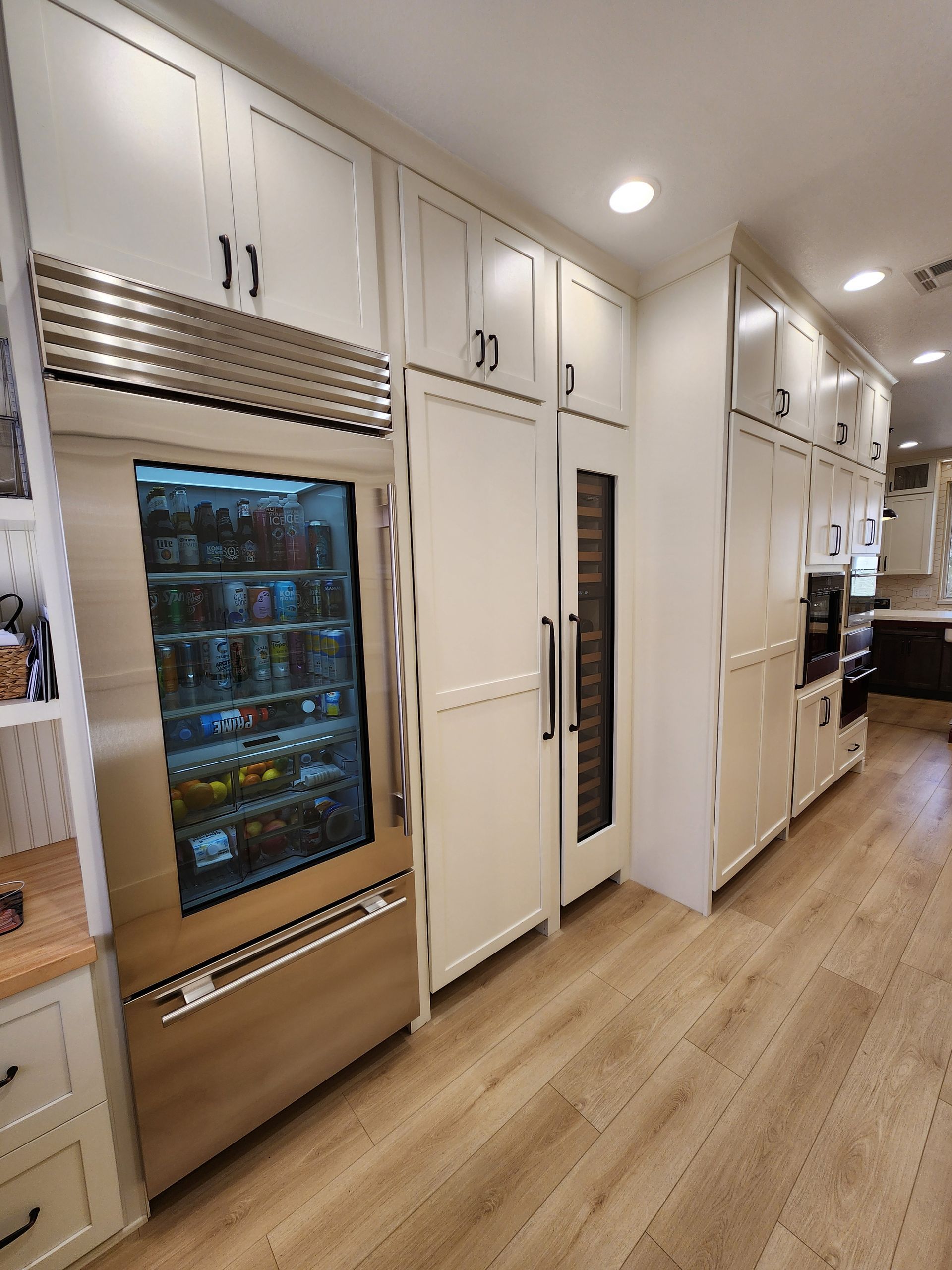 Modern kitchen with white cabinets, wood floors, built-in refrigerator, and a long counter area