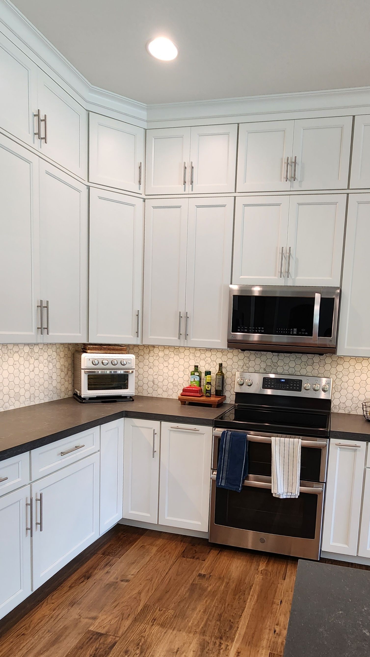 Bright kitchen with white cabinets, black appliances, mosaic backsplash, and wood floor