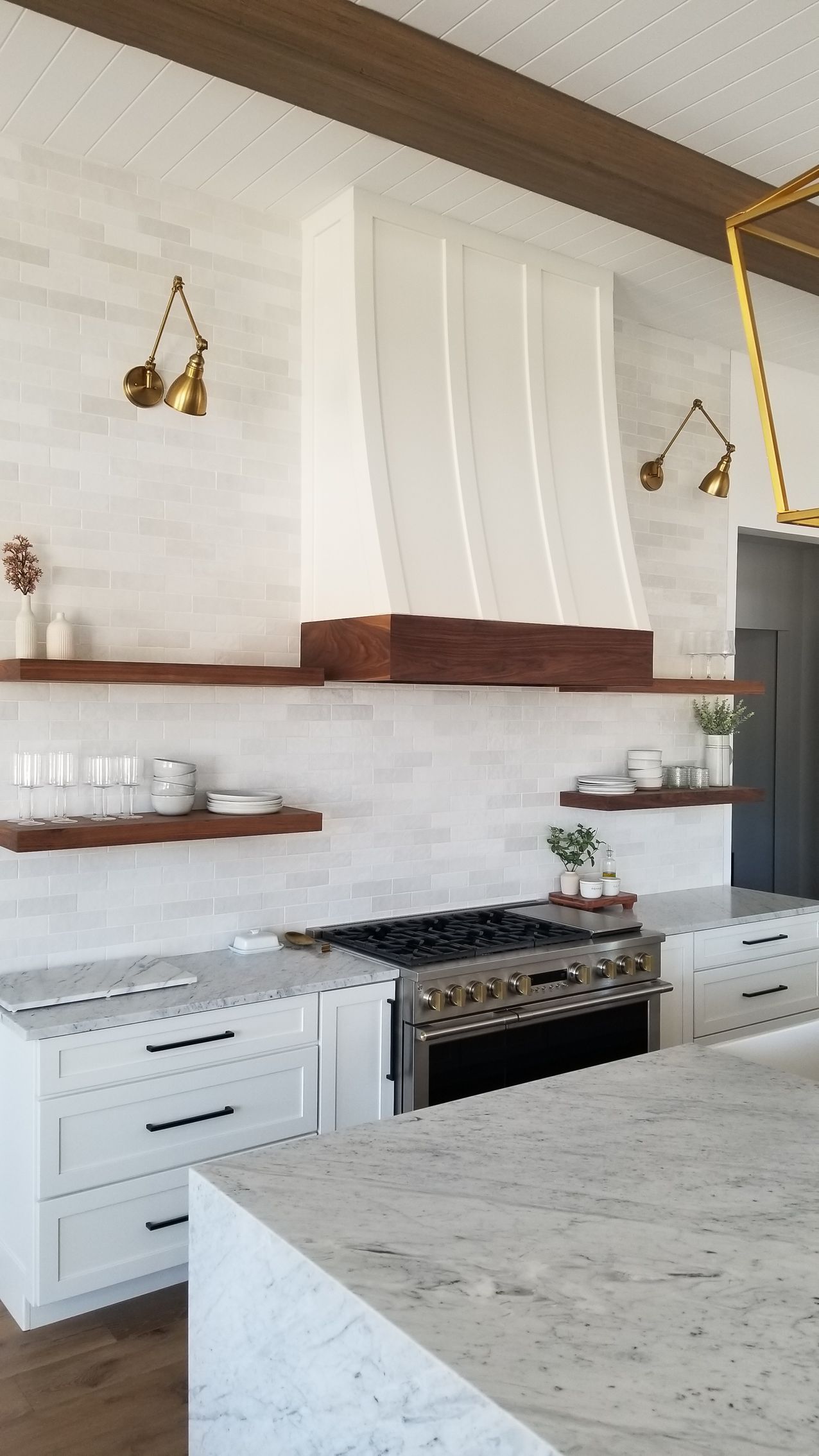Bright kitchen with white cabinets, wood accents, granite island, and a stainless steel range hood