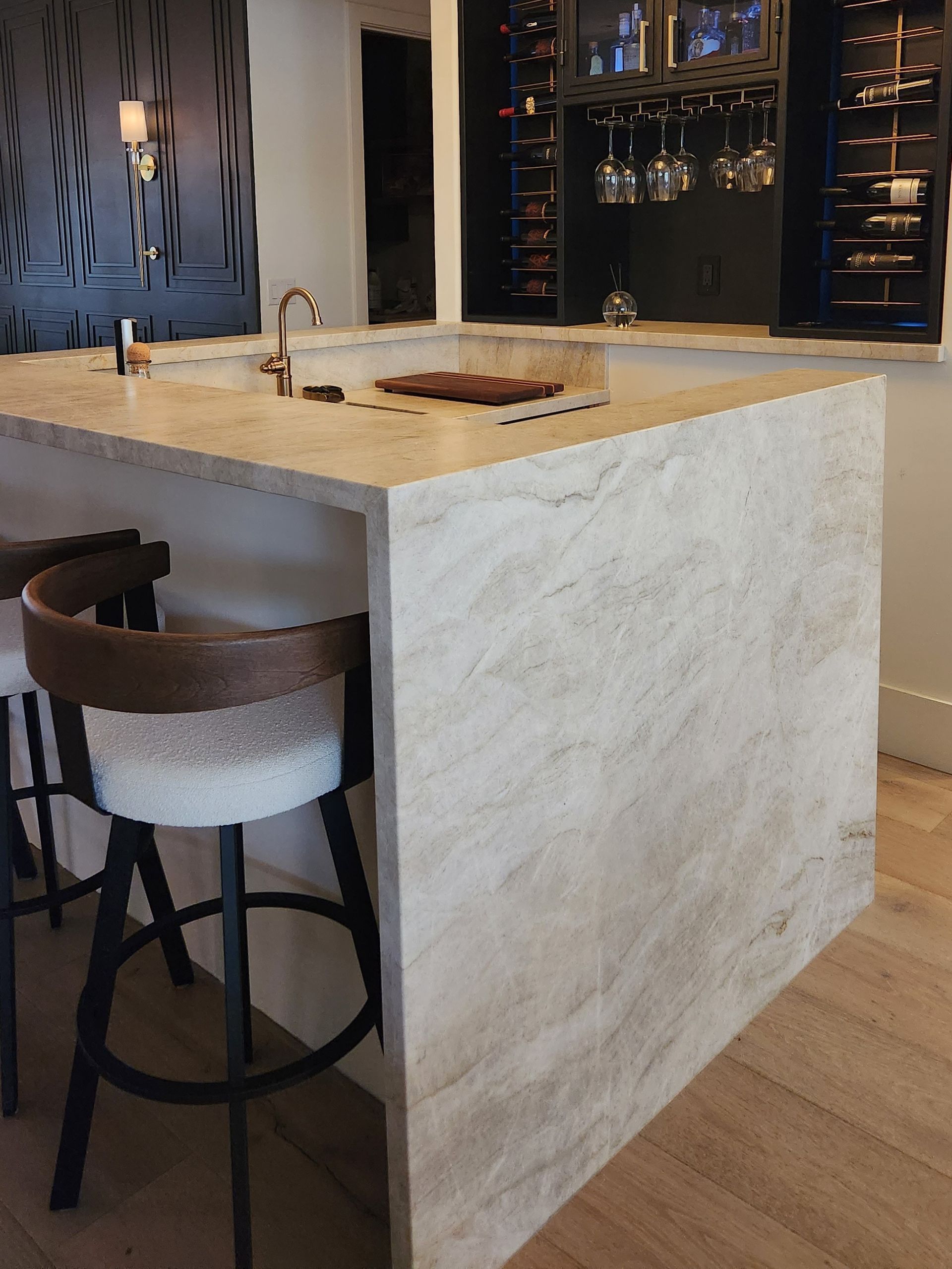 Modern kitchen island with marble countertop, bar stool, pendant lights, and open shelving in a contemporary interior