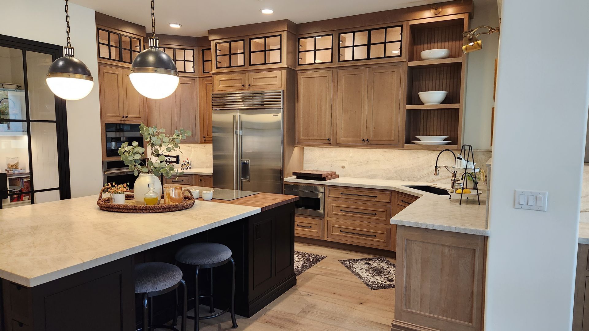 Modern kitchen with wood cabinets, stainless fridge, large island, and pendant lights
