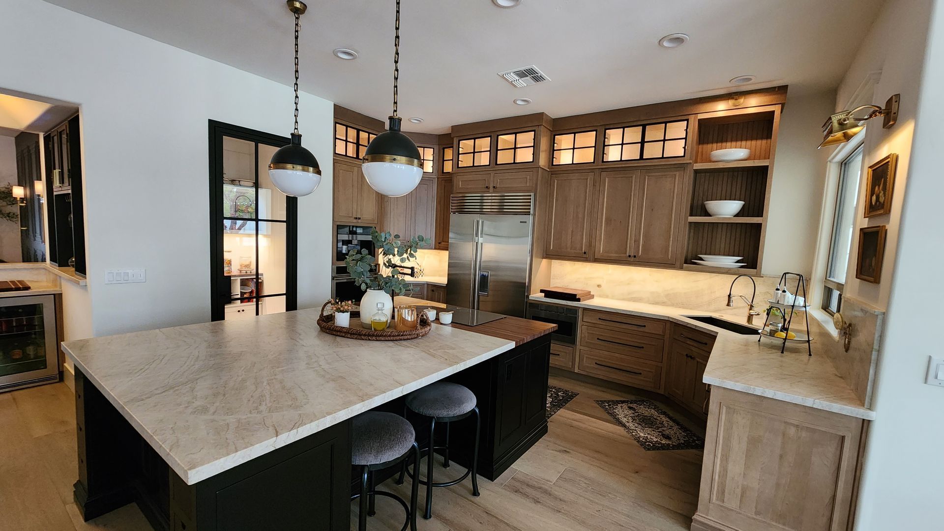 Modern kitchen with island, pendant lights, wood cabinets, and a dining table with stools