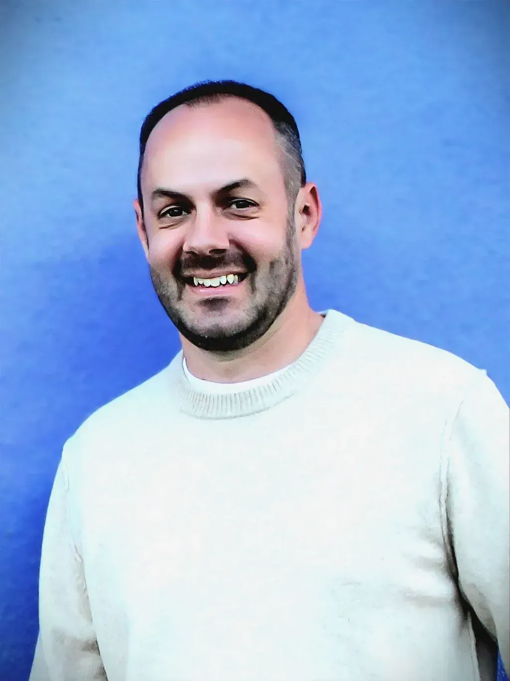 Smiling man in a gray striped polo shirt against a white background