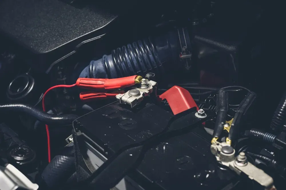 Car battery with red jumper cables attached. — Ben's Tyres in Gulgong, NSW