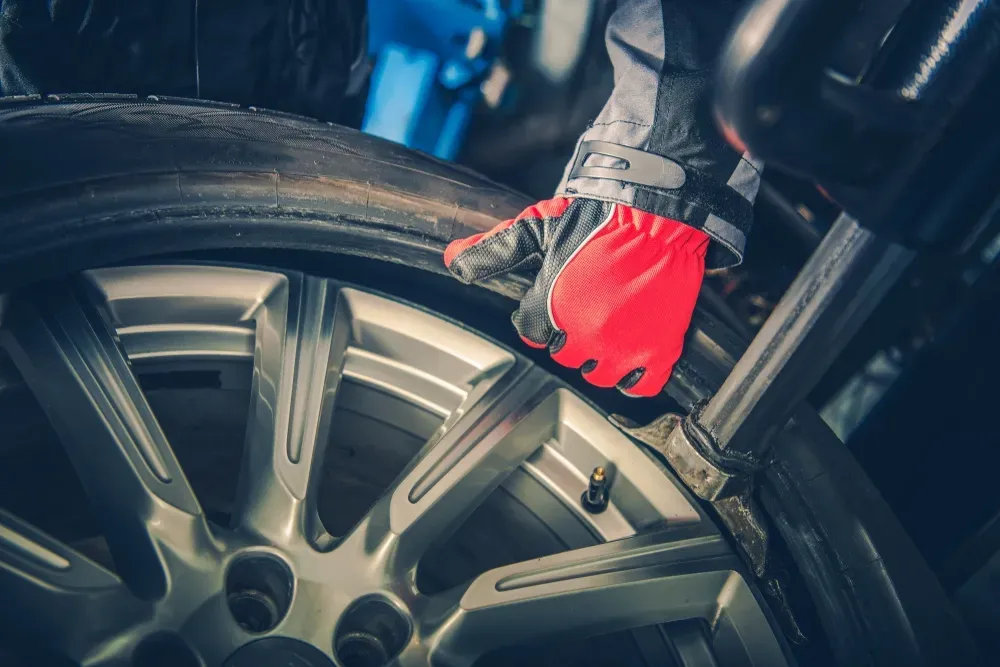 A mechanic's gloved hand touching a car tire rim in a shop. — Ben's Tyres in Yeoval, NSW