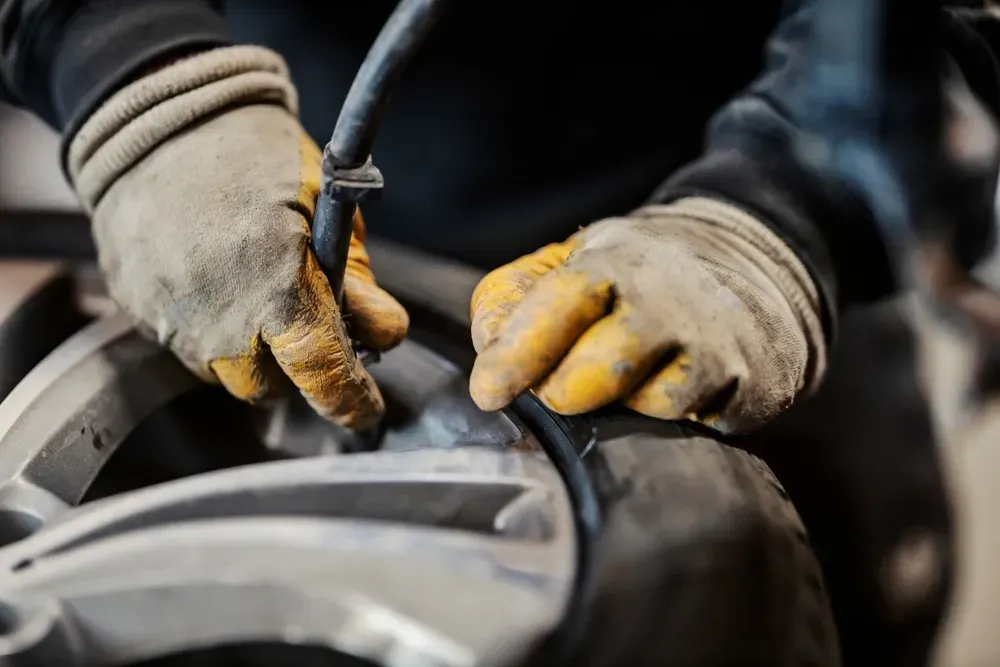 Hands in work gloves placing a black rubber seal on a silver wheel. — Ben's Tyres in Mudgee, NSW