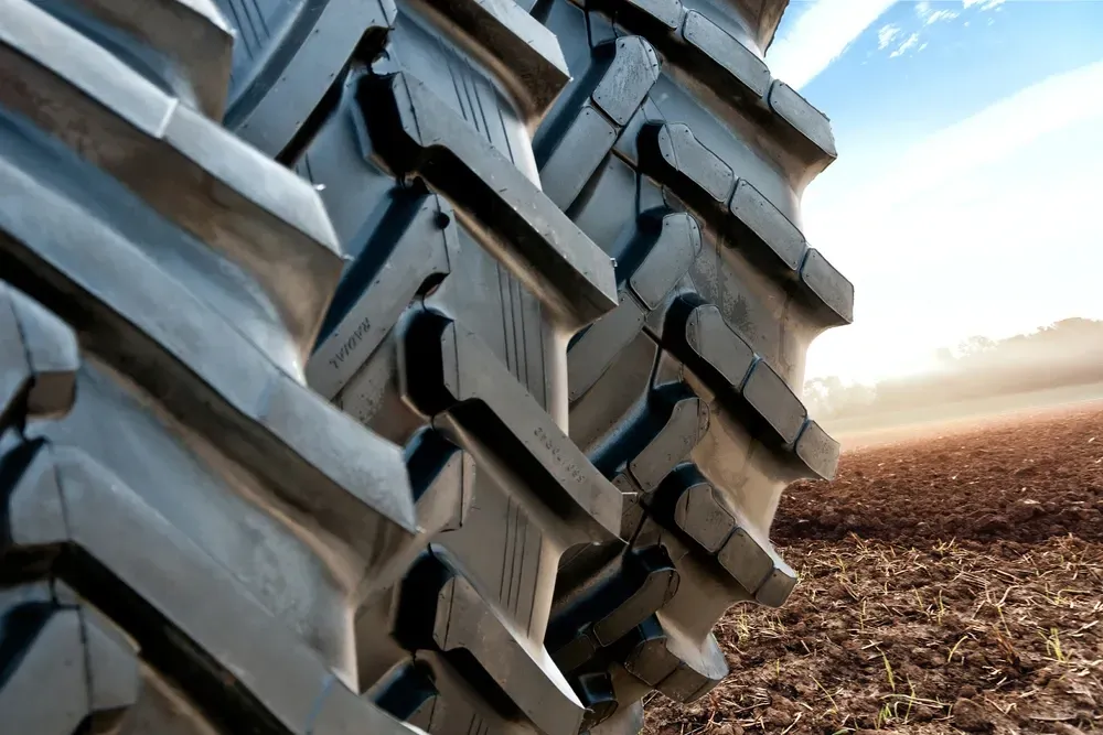 Close-up of tractor tire tread in front of a harvested field under a blue sky. — Ben's Tyres in Gulgong, NSW