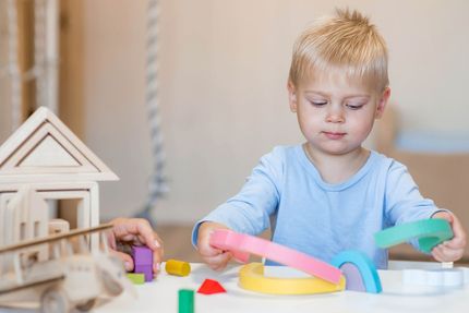 A little boy is sitting at a table playing with toys.