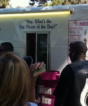 Food truck window with sign “Hey, What’s the New Flavor of the Day?” and people waiting in line