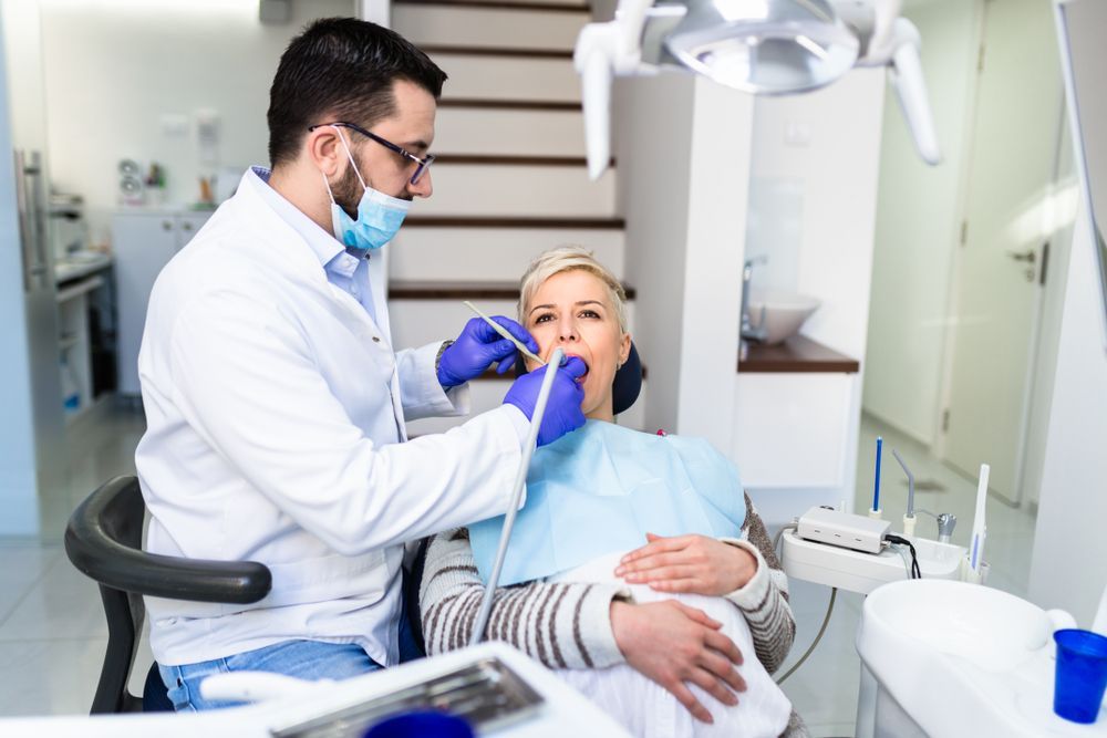 Dentist examining a female patient's teeth in a modern dental office.