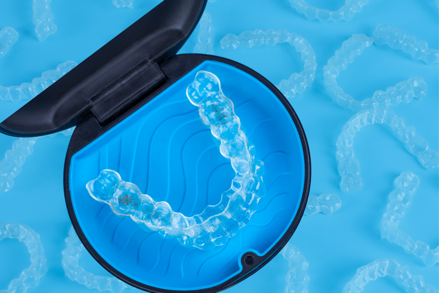 Woman inserting clear aligners into her mouth, smiling; close-up.