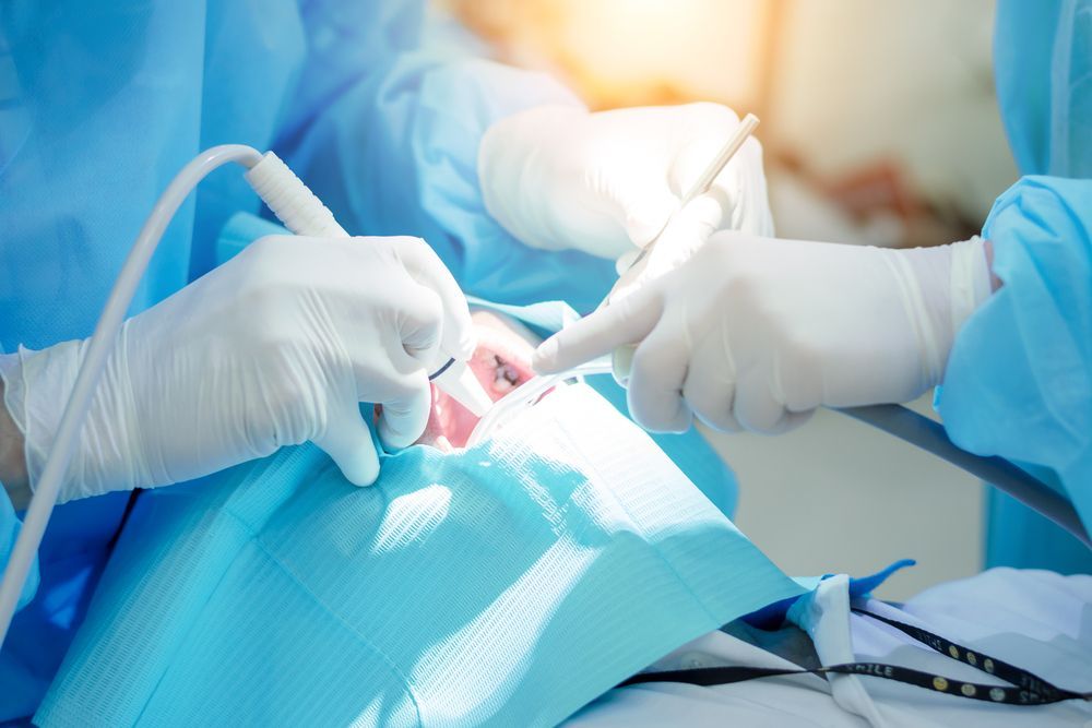 Mouth open, showing a dental procedure: gum incision, teeth, clear mouth guard, surgical tool.