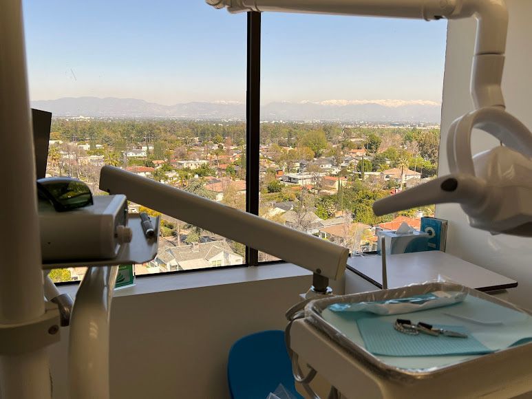 Farzad Dental office with a city view, equipment in the foreground, and a bright sky.