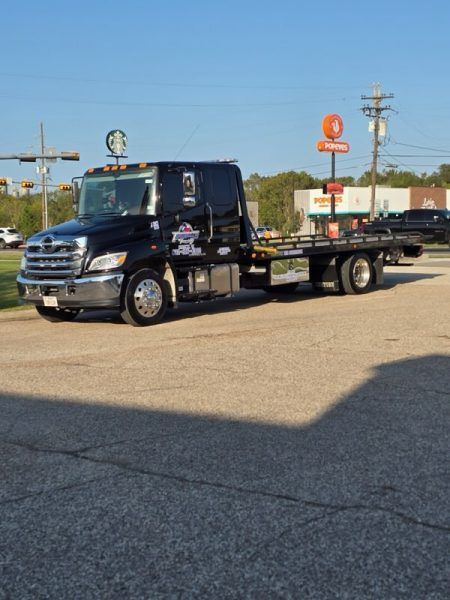 A black tow truck is parked in a parking lot