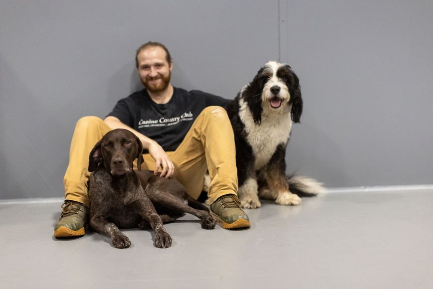 A man is sitting on the floor with two dogs.