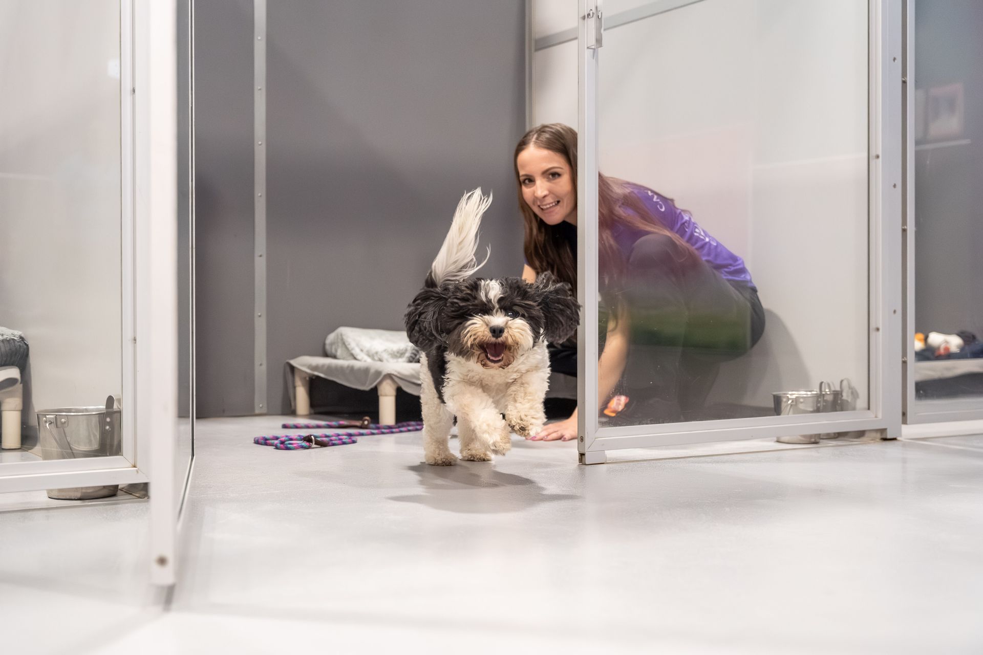 A woman is standing next to a dog in a kennel.