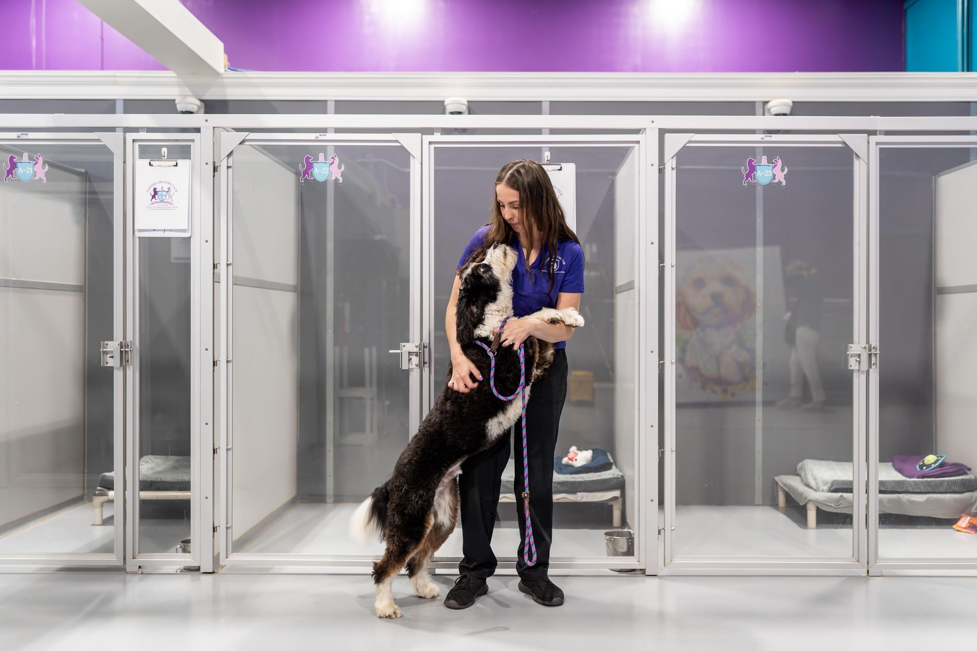 A woman is standing next to a dog in a kennel.