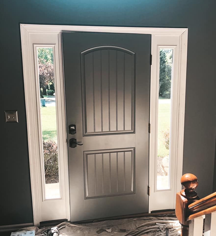 Gray front door with sidelights, white trim, and dark gray walls.