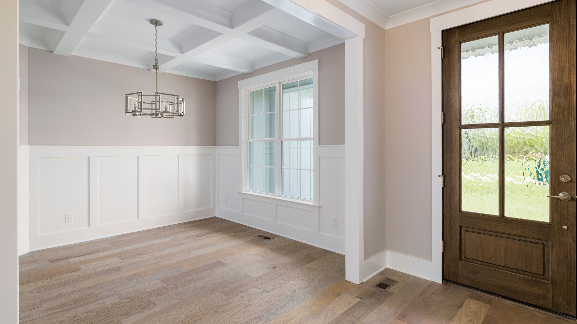 Interior room with beige walls, white trim, hardwood floors, and a brown door with glass panes.