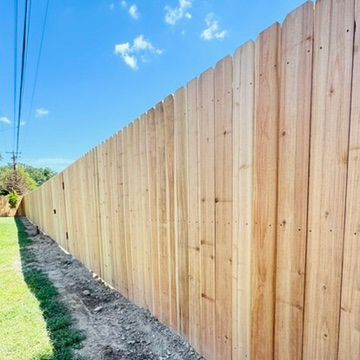 Wooden privacy fence along a grassy yard under a blue sky.